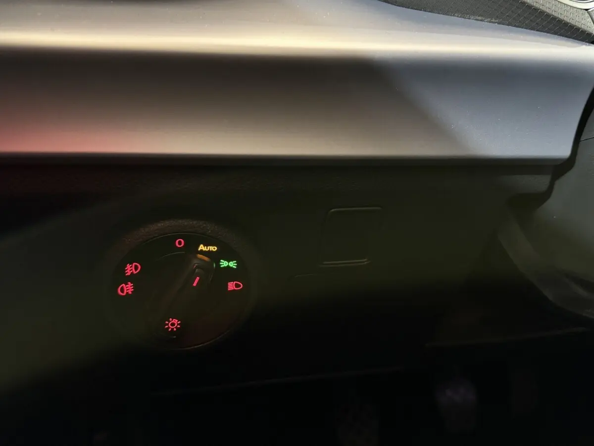 Gros plan sur le bouton de commande des phares dans l'habitacle sombre d'une SEAT Ibiza blanche 2024.