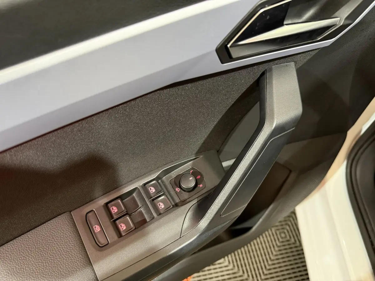 Vue rapprochée de la porte avant gauche blanche de la SEAT Ibiza 2024 avec commandes électriques des vitres et rétroviseurs.