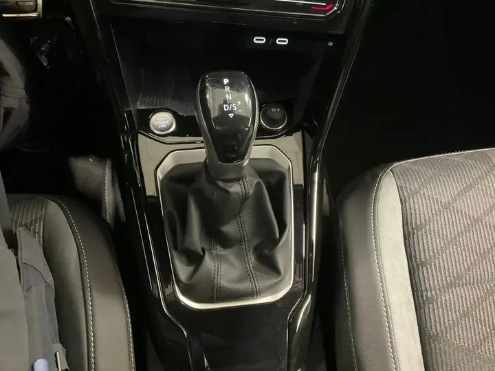 Vue rapprochée de la console centrale noire du Volkswagen T-Roc 2025 avec levier de vitesse automatique et bouton start/stop.