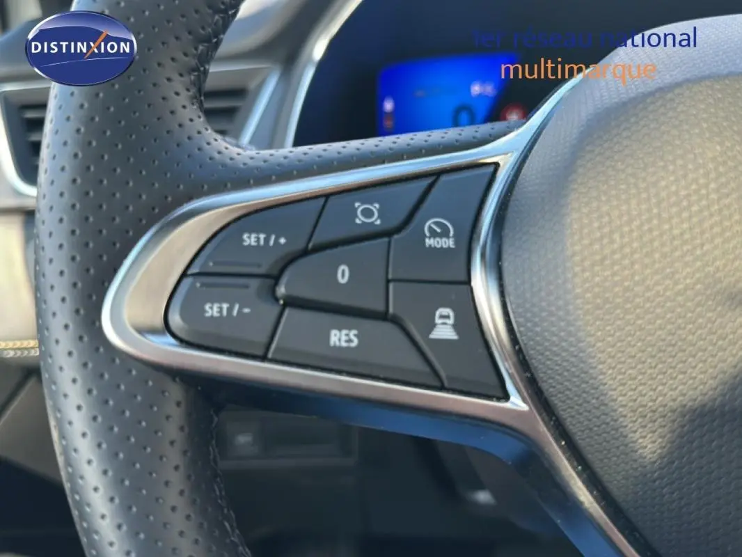 Gros plan sur le côté gauche du volant perforé du Renault Symbioz blanc, avec commandes de régulateur de vitesse.