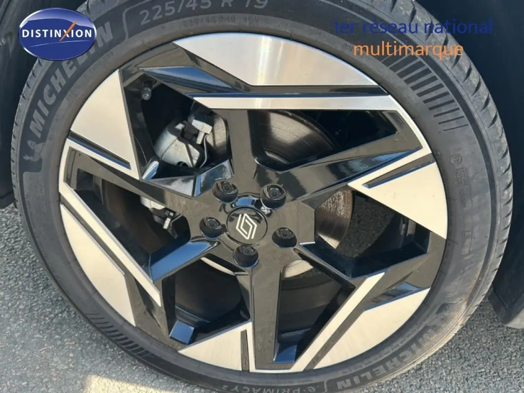 Gros plan sur la jante alliage 19 pouces noire et argentée d'une Renault SYMBIOZ blanc, version E-Tech full hybrid 145 Iconic.