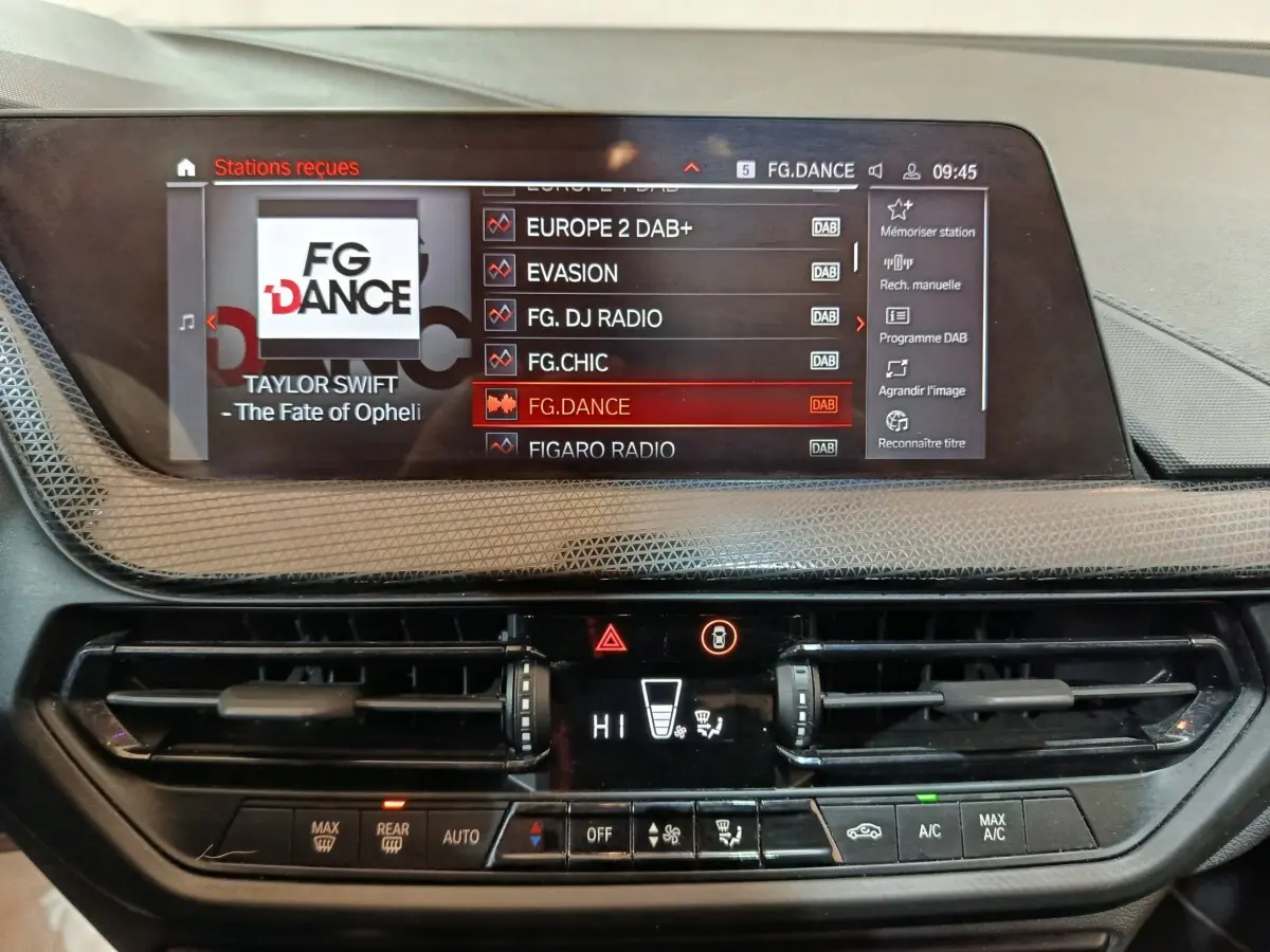 Vue rapprochée du tableau de bord de la BMW Série 1 noire, affichant l'écran tactile multimédia et la console de climatisation.