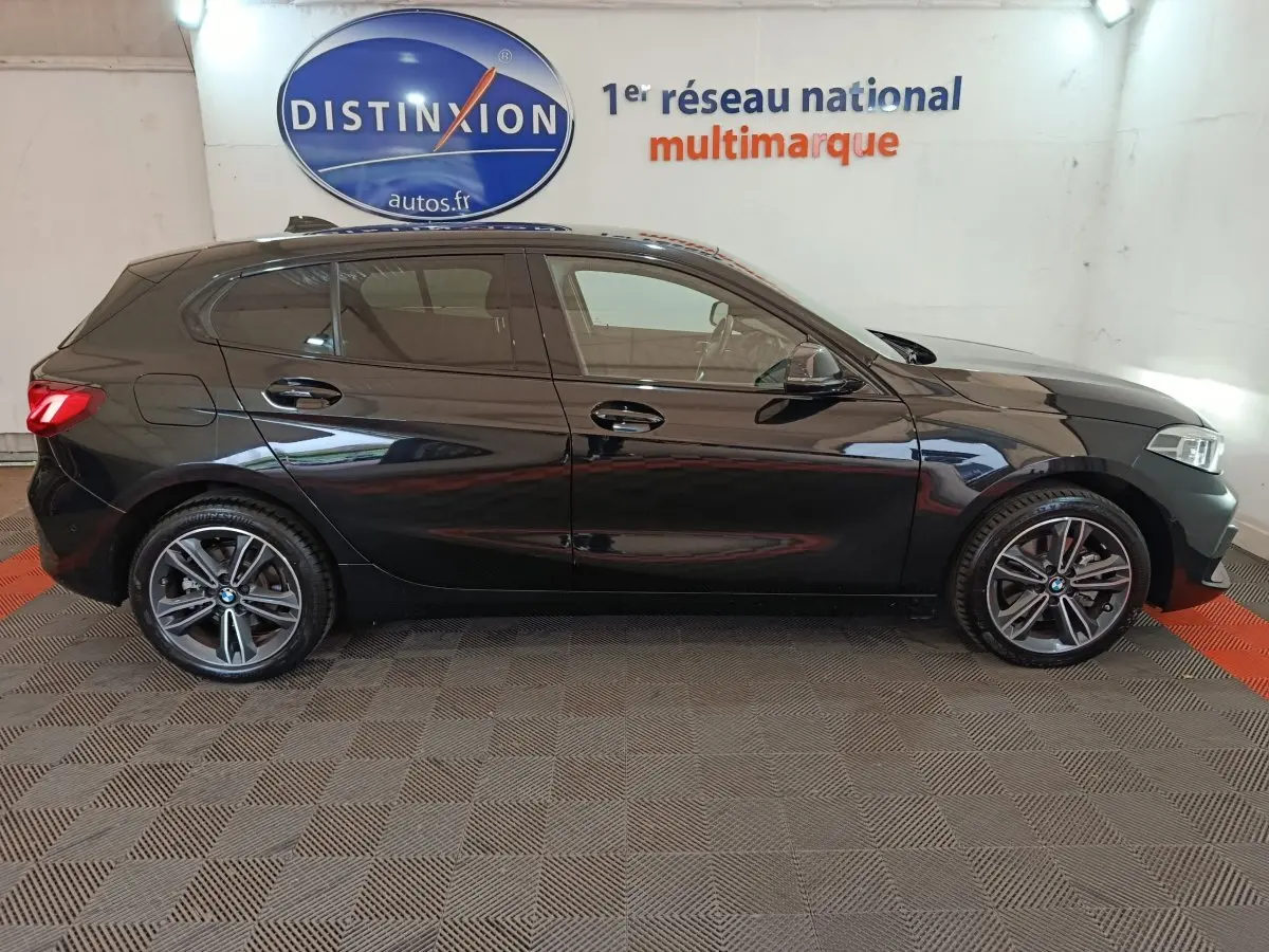 BMW Série 1 118i Edition Sport noire vue de profil côté gauche, jantes alliage et feux arrière LED visibles.