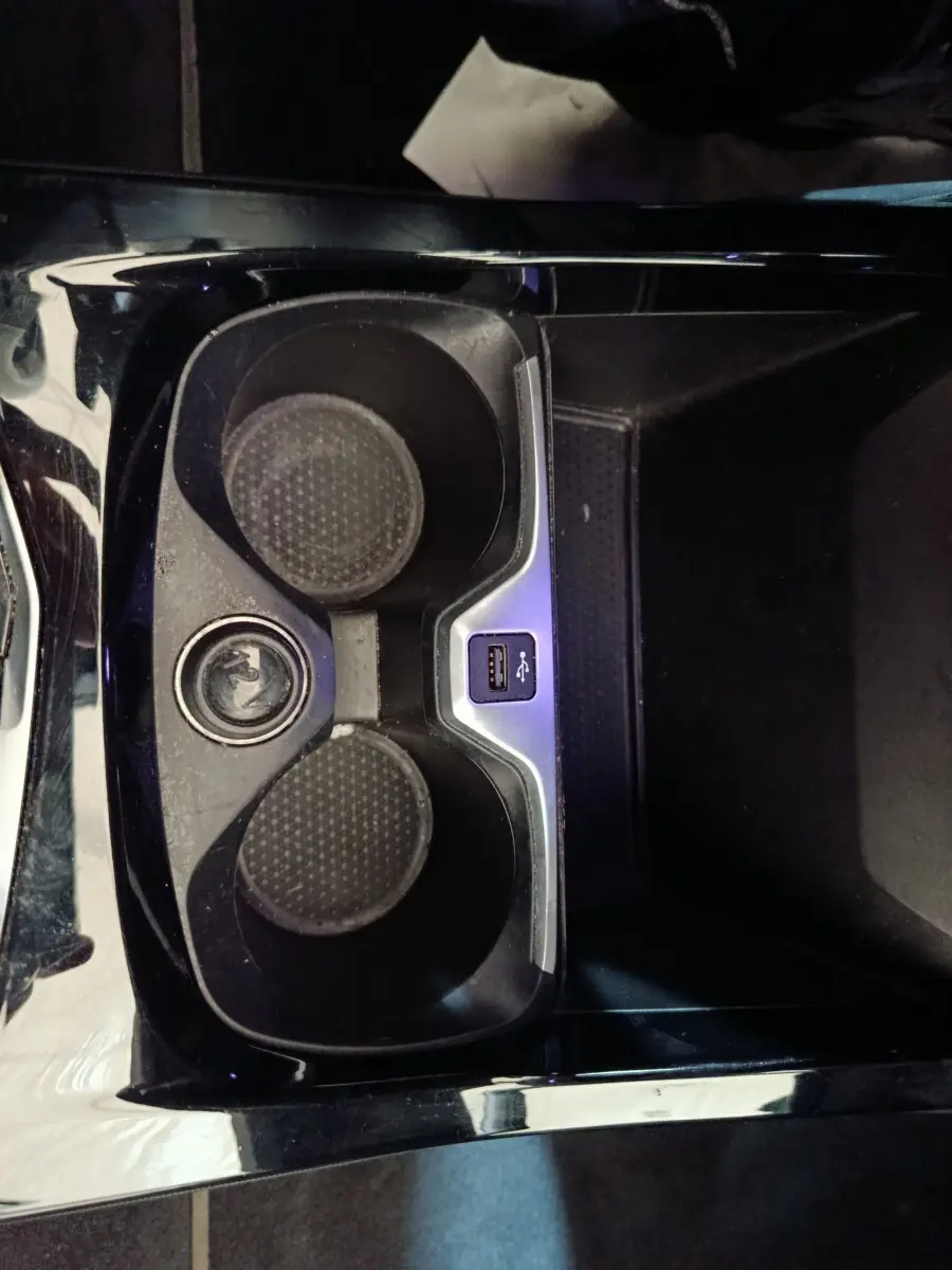 Vue plongeante sur le porte-gobelets noir brillant avec prise USB intégré dans une BMW Série 1 118i Edition Sport 2023.