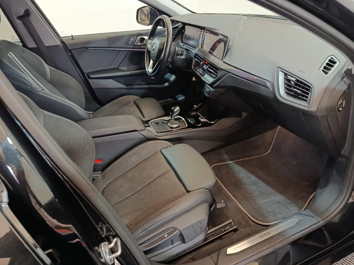 Intérieur noir de la BMW Série 1 118i Edition Sport 2023, vue côté conducteur avec tableau de bord et console centrale.