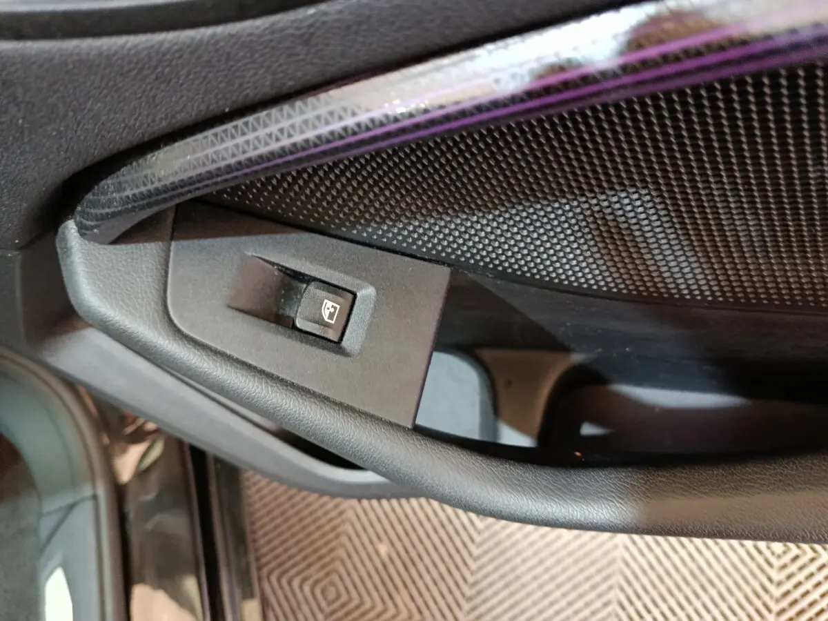 Détail de la commande de lève-vitre côté conducteur sur la porte intérieure noire d’une BMW Série 1 118i Edition Sport 2023.