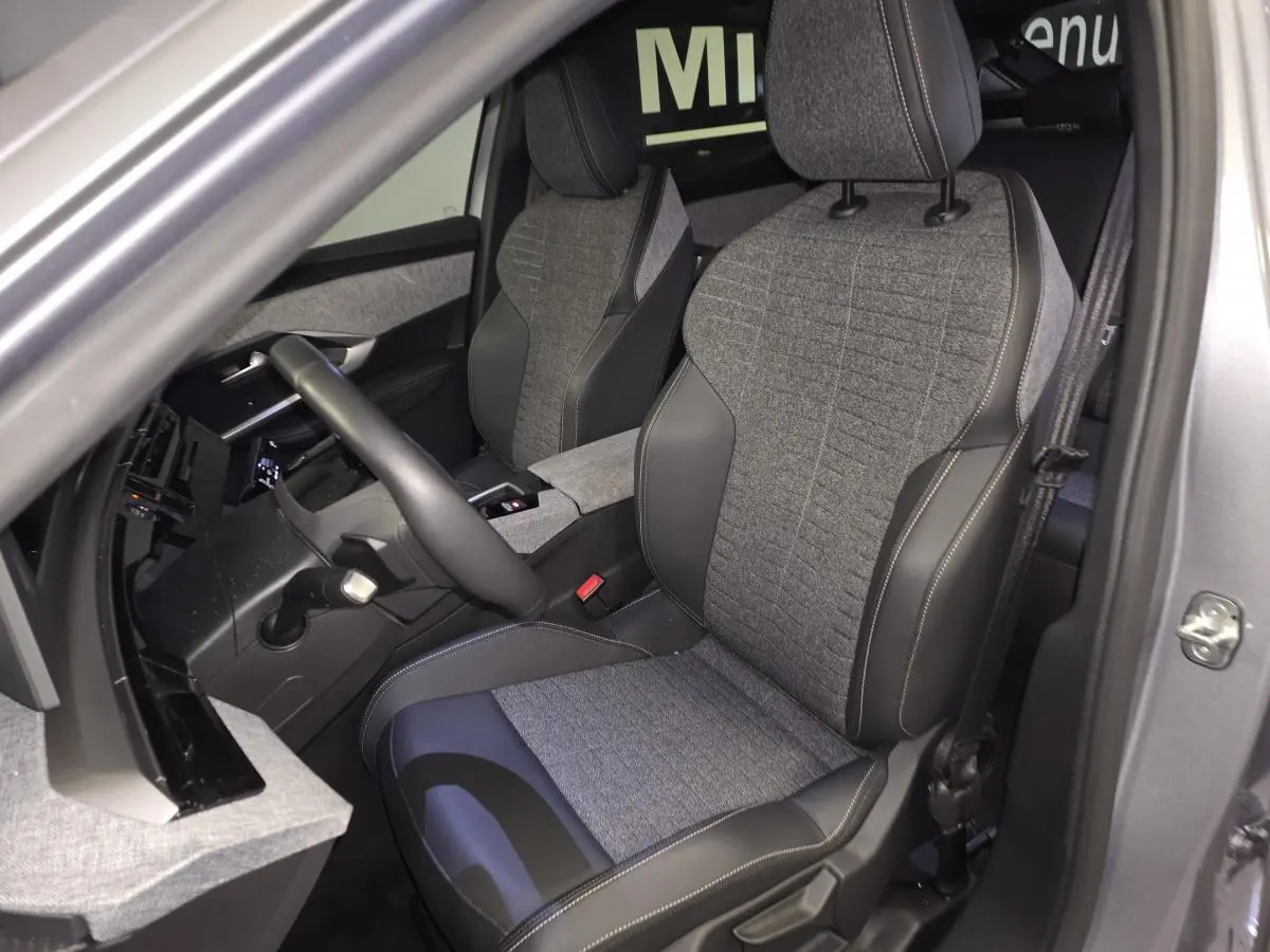 Vue intérieure côté conducteur du Peugeot 3008 gris 2025, sièges tissu gris et cuir noir avec surpiqûres quartz.