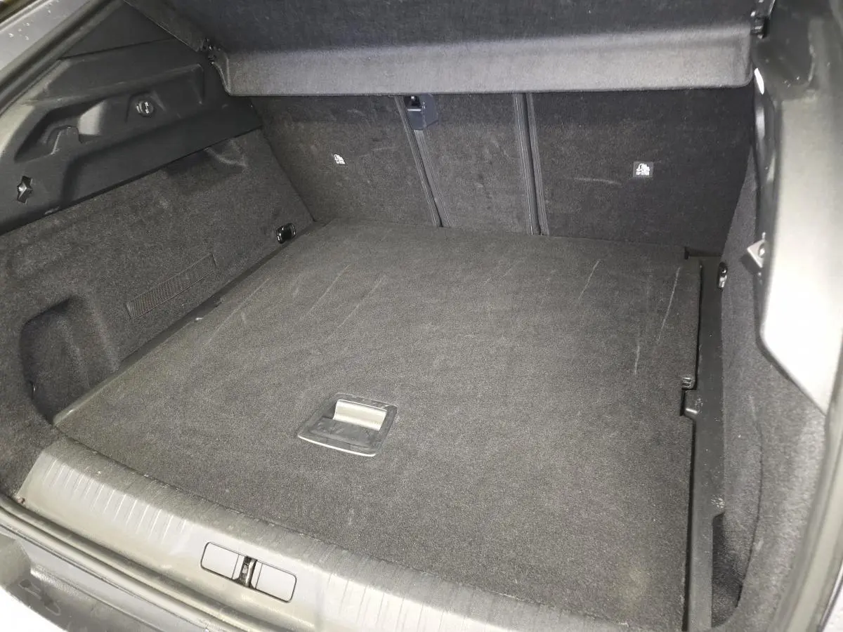 Coffre ouvert du Peugeot 3008 gris, montrant le plancher plat et les dossiers arrière rabattus.