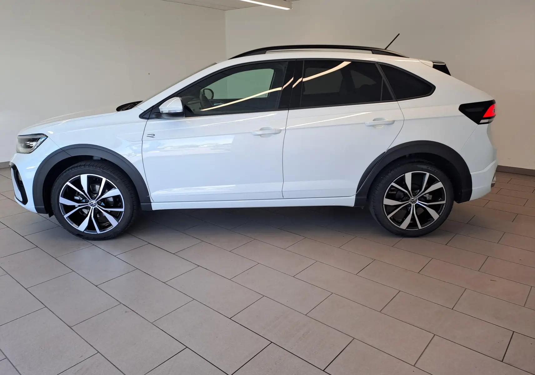Vue de profil côté gauche du Volkswagen Taigo blanc pur 2025 avec jantes alliage noir et argent 18 pouces R-Line Edition.