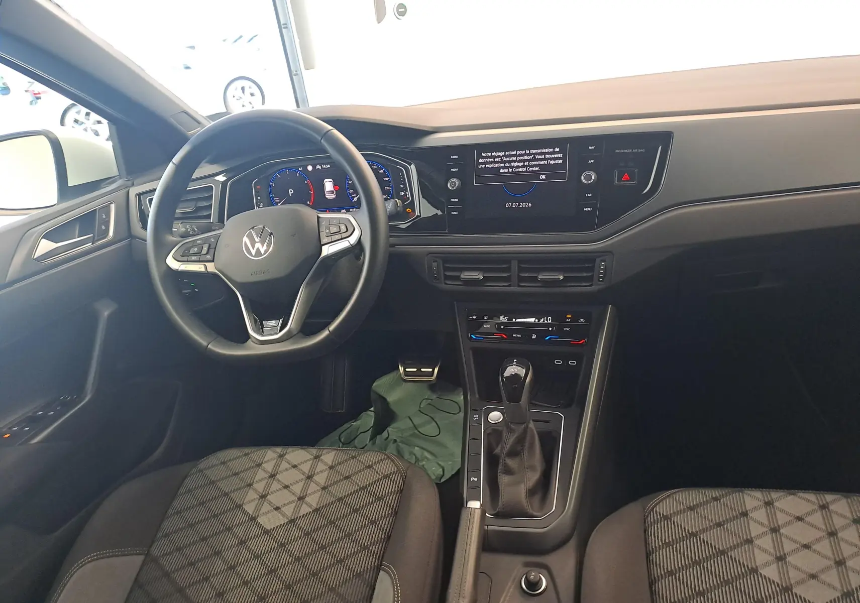 Vue intérieure du tableau de bord et volant du Volkswagen Taigo 1.0 TSI R-Line Edition avec écran digital et sellerie tissu noire.