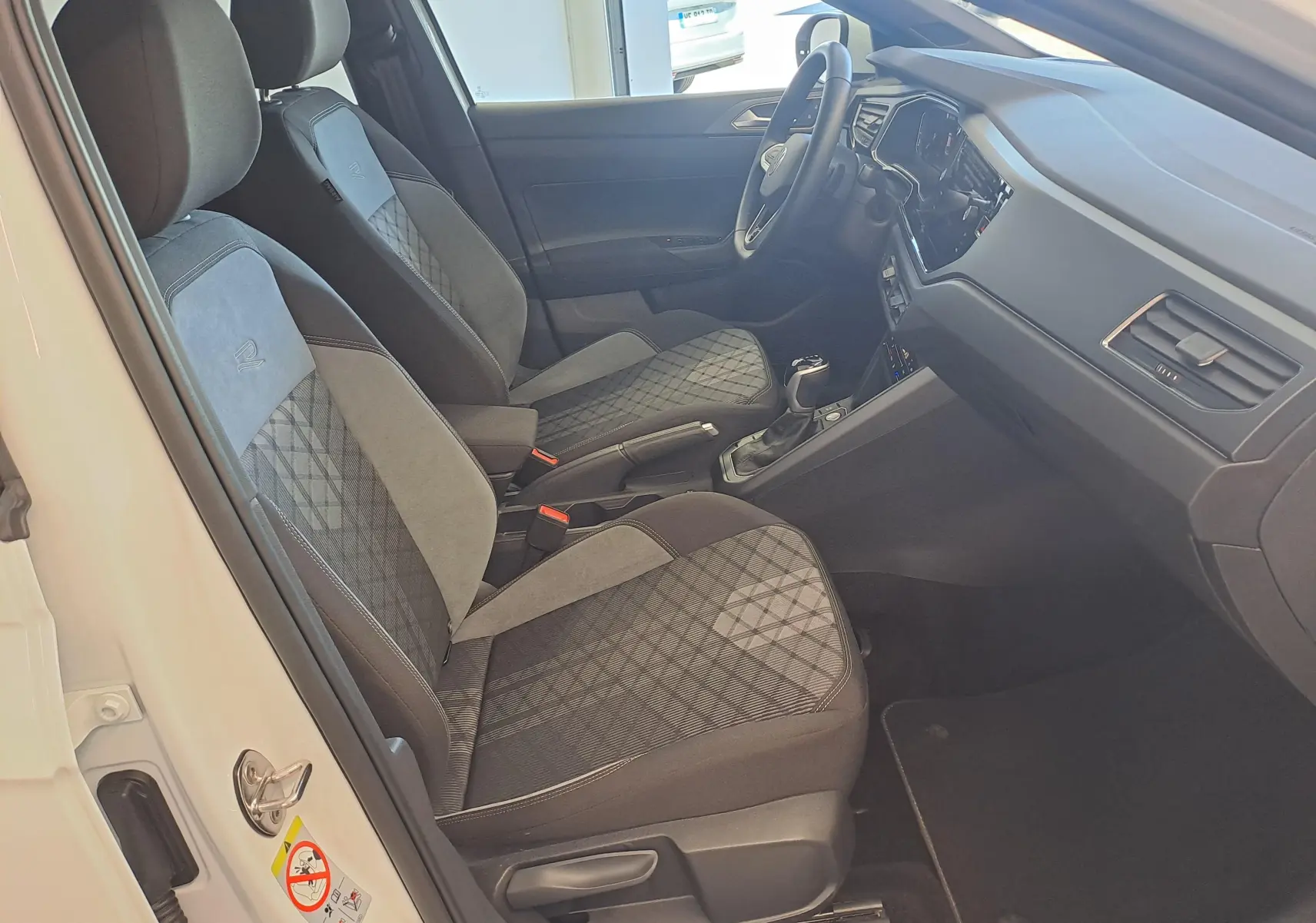 Vue intérieure côté conducteur du Volkswagen Taigo blanc, sièges tissu et alcantara avec surpiqûres R-Line.