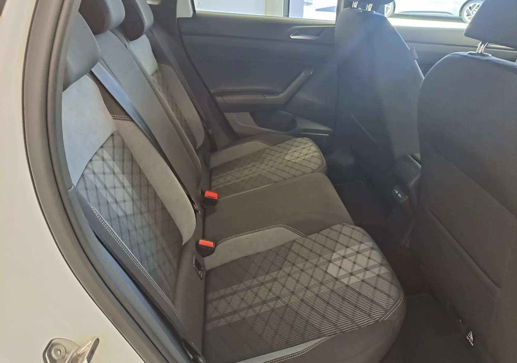Vue intérieure arrière gauche du Volkswagen Taigo 2025, sièges en tissu noir et gris avec motifs géométriques.