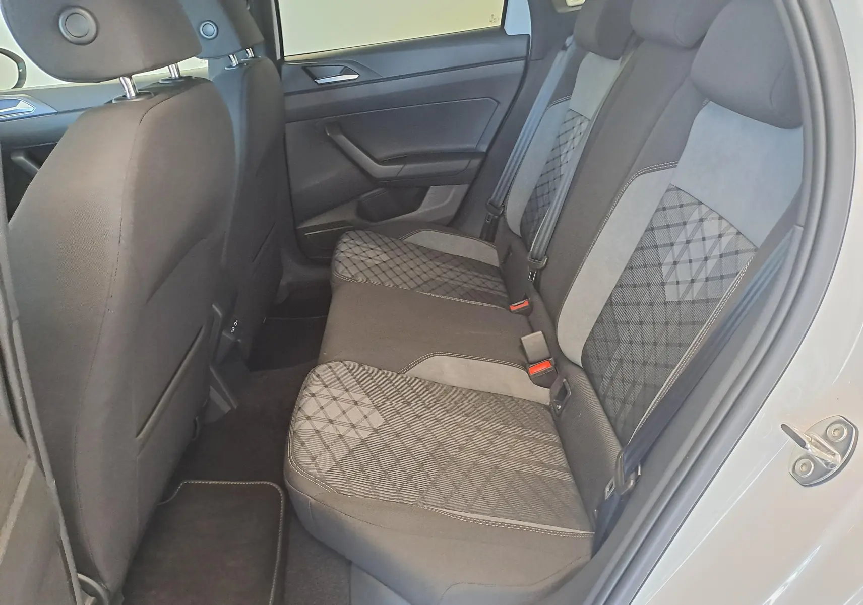 Vue intérieure côté droit des sièges arrière du Volkswagen Taigo 2025 avec sellerie tissu gris à motifs géométriques.