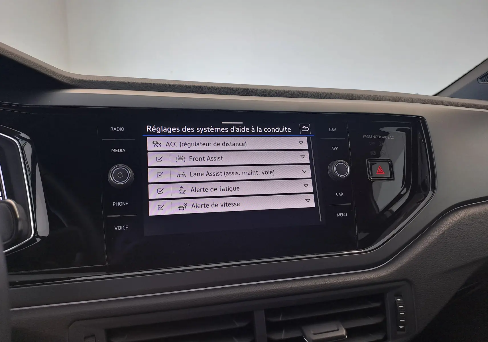 Écran tactile central du Volkswagen Taigo 2025 affichant les réglages des aides à la conduite dans un intérieur noir.