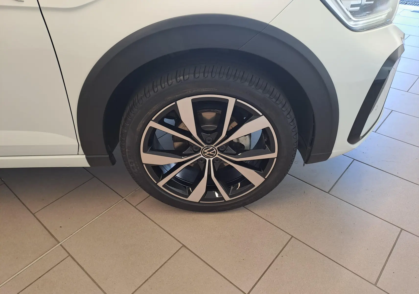 Gros plan sur la roue avant droite du Volkswagen Taigo blanc pur, jante alliage léger 18 pouces Misano bicolore.