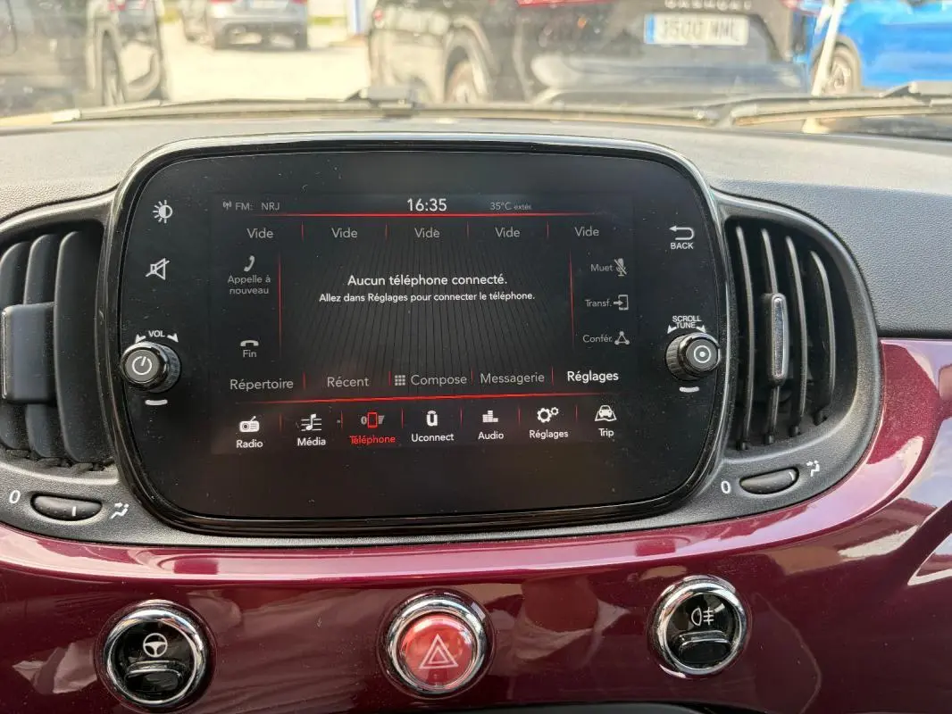 Tableau de bord violet d'une Fiat 500 2019, avec écran tactile central et commandes de climatisation visibles.