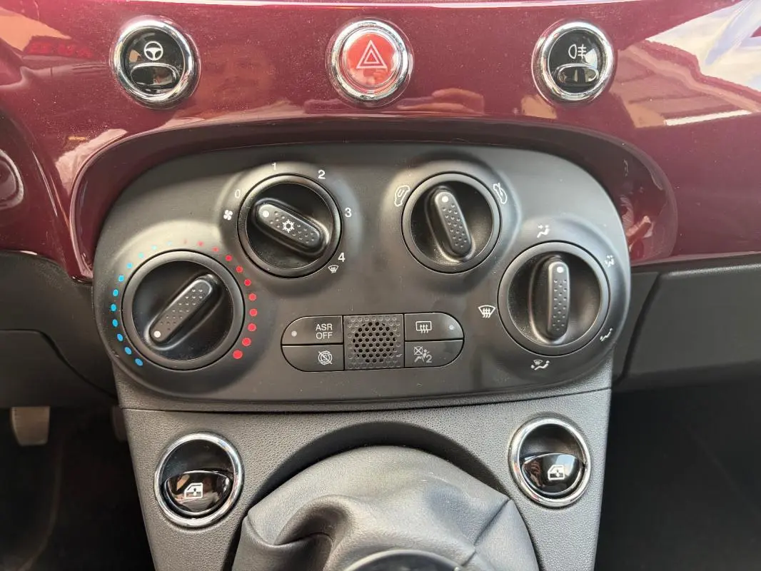 Vue rapprochée des commandes de climatisation et ventilation sur le tableau de bord violet de la Fiat 500 Lounge 2019.