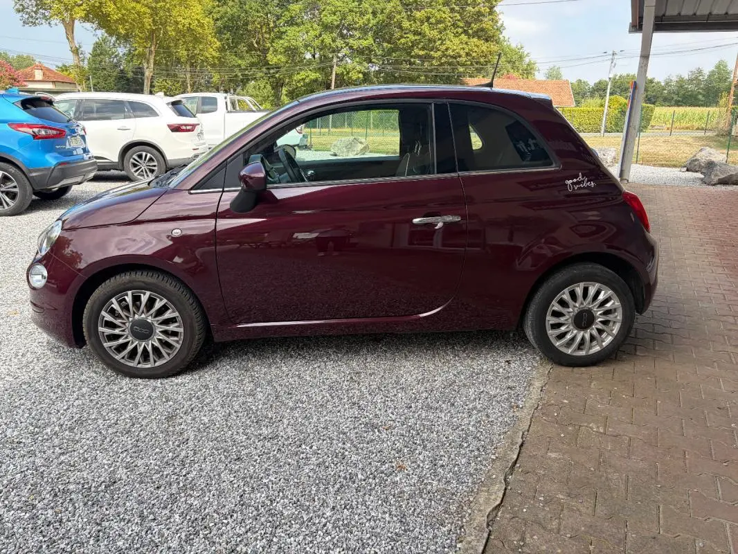 Profil côté gauche d'une FIAT 500 berline violet foncé de 2019 avec jantes alliage et sticker "good vibes" arrière.