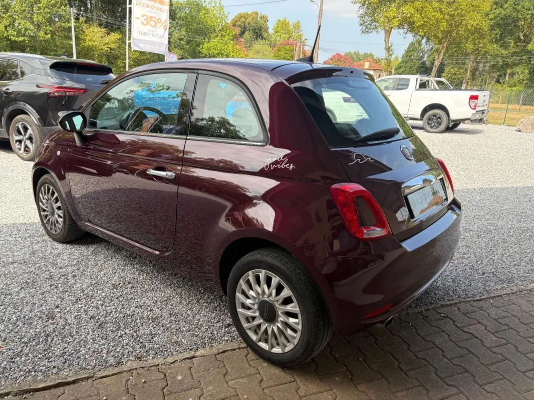Vue 3/4 arrière droite d'une FIAT 500 berline violet foncé avec jantes alliage et stickers décoratifs sur l'aile arrière.