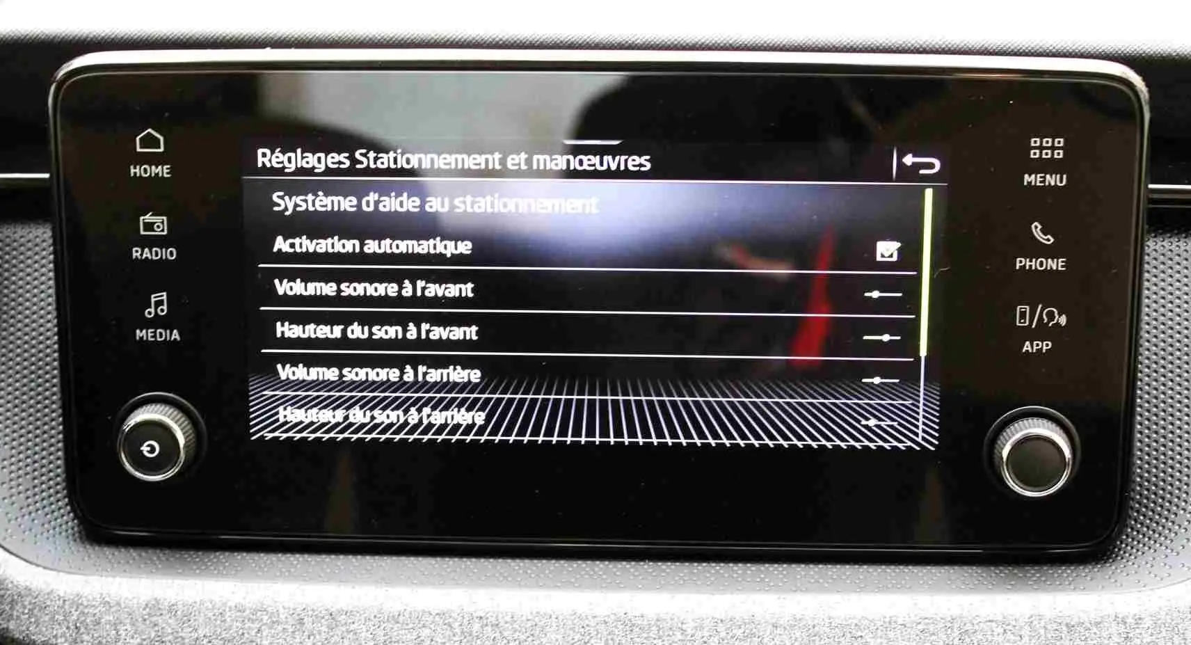 Écran tactile central du Skoda Kamiq 2025 affichant les réglages d'aide au stationnement avec commandes physiques autour.