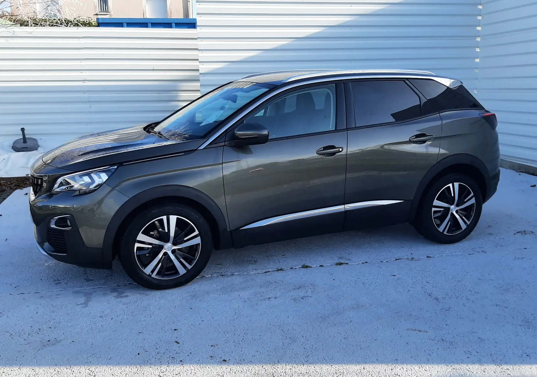 Peugeot 3008 gris amazonite en vue de profil côté gauche, avec jantes alliage bicolores et vitres teintées.