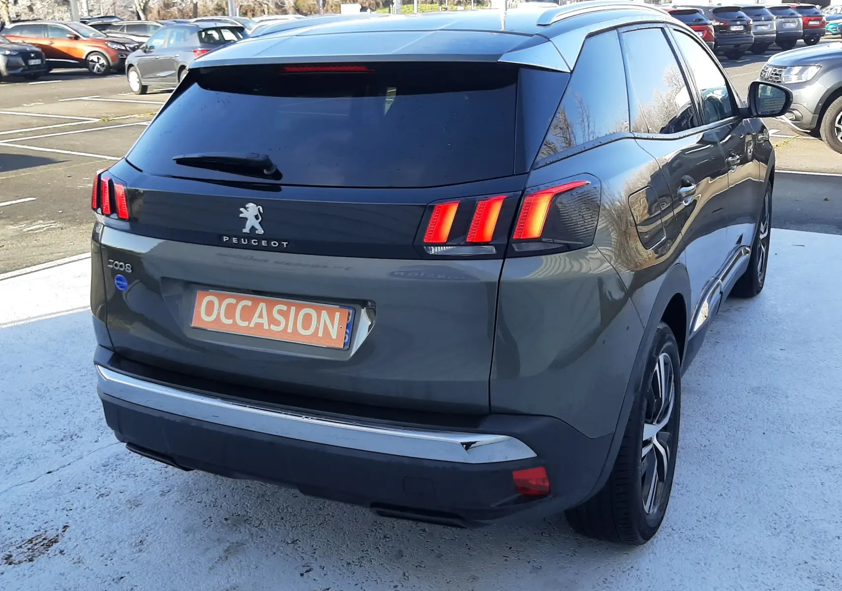 Vue 3/4 arrière droite d'un Peugeot 3008 gris amazonite avec feux arrière allumés et vitre teintée.