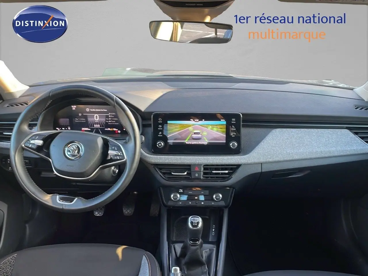 Vue intérieure frontale du tableau de bord du Skoda Kamiq 2024 gris graphite, avec volant multifonction et écran tactile central.