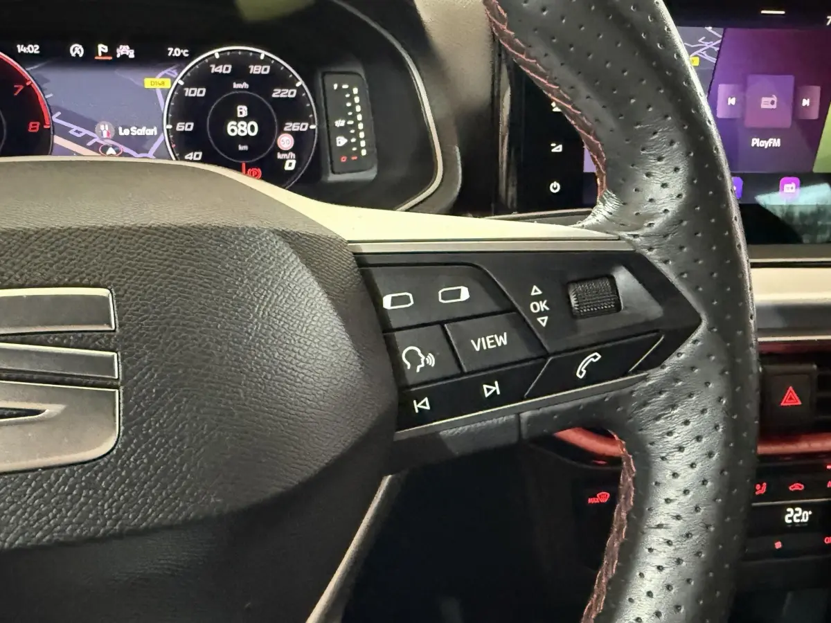 Gros plan sur le volant cuir perforé avec commandes multifonctions, tableau de bord digital et écran tactile de la SEAT Ibiza blanche 2024.