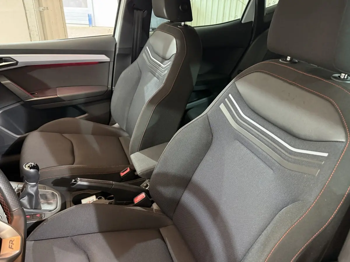 Vue intérieure côté droit de la SEAT Ibiza 1.0 TSI 110 FR 2024, sièges noirs avec surpiqûres rouges et levier de vitesses manuel.