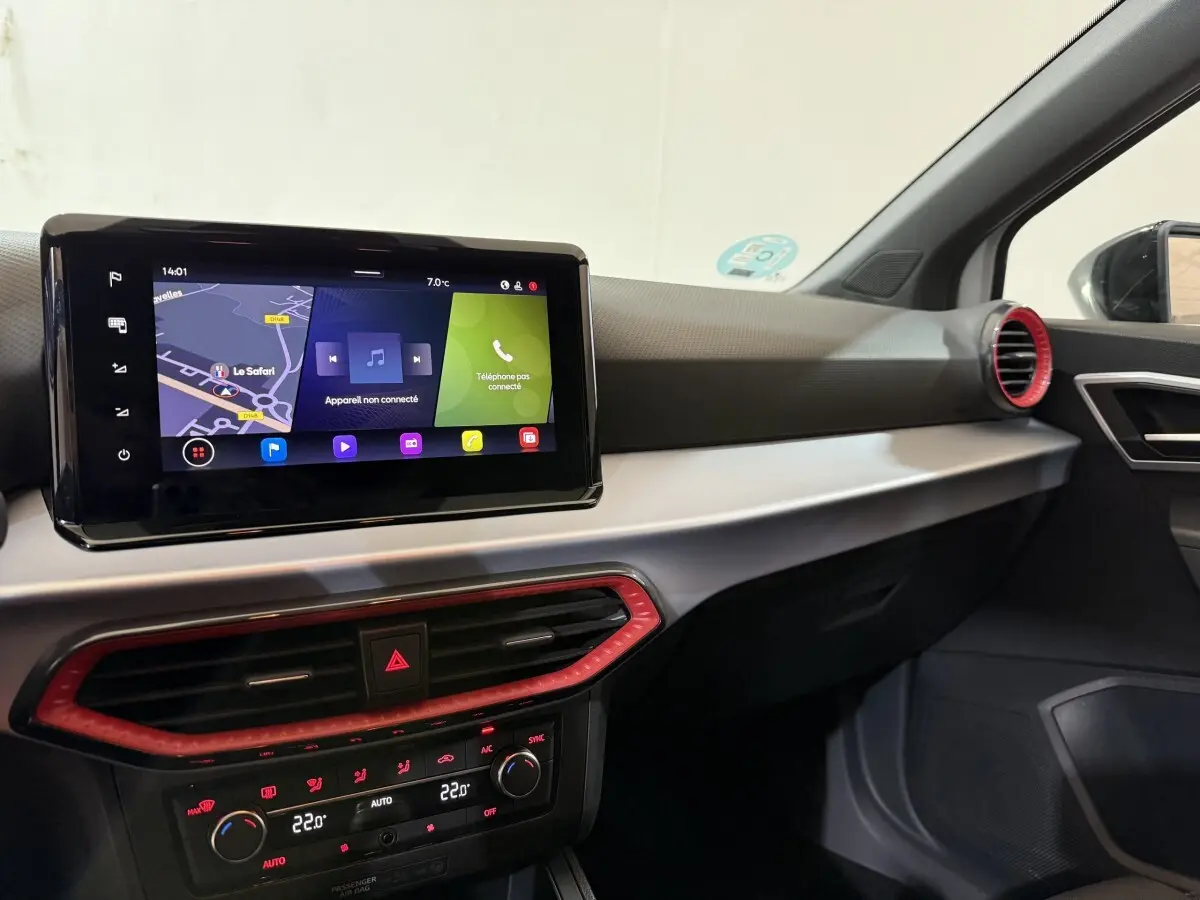 Vue intérieure côté passager du tableau de bord de la SEAT Ibiza blanc avec écran tactile et aérateurs rouges.