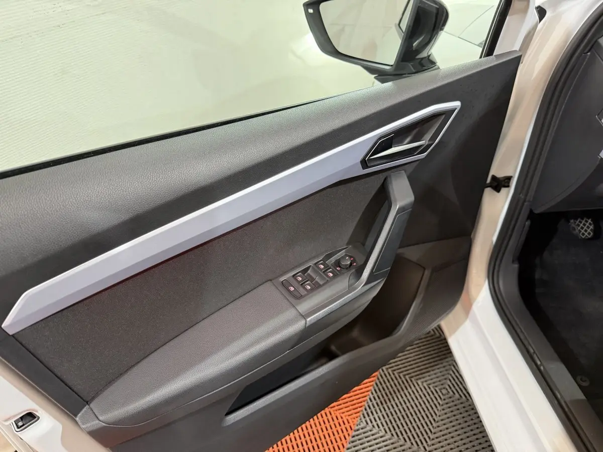 Vue rapprochée de la porte avant gauche blanche d’une SEAT Ibiza 2024 avec commandes électriques et poignée alu.