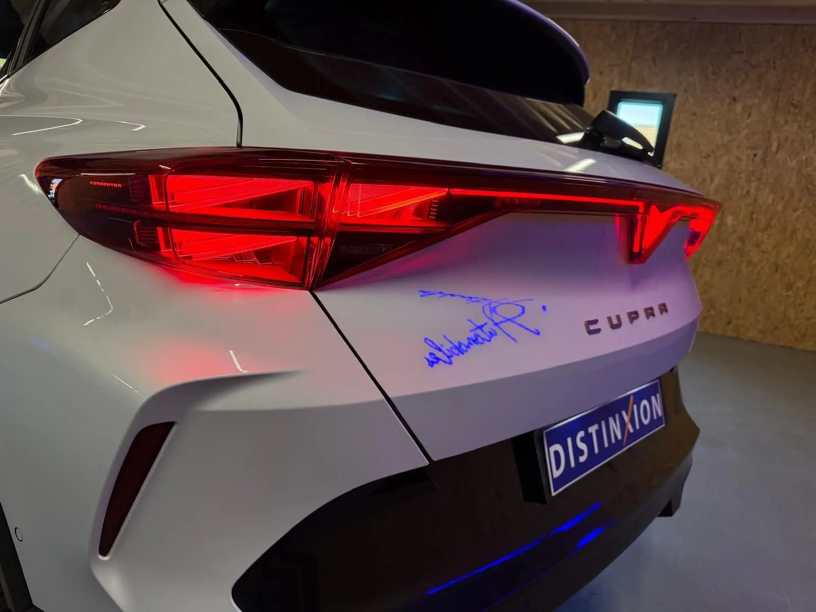 Vue 3/4 arrière droite du CUPRA Formentor blanc avec feux arrière allumés et logo CUPRA visible sur le hayon.