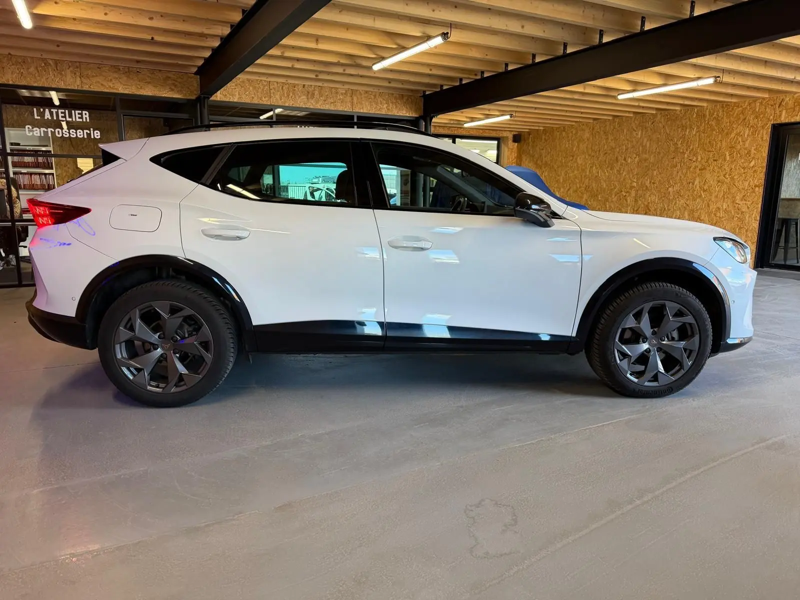 Profil côté gauche d’un CUPRA Formentor blanc 2025 avec jantes noires et entourage de vitres noir piano.