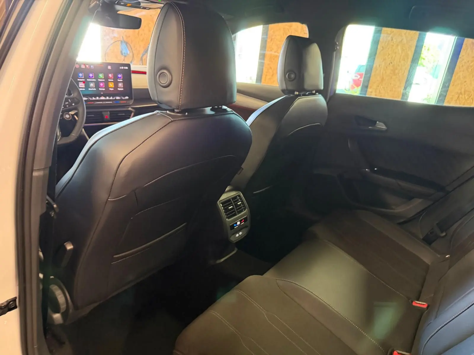 Vue intérieure arrière droite du CUPRA Formentor blanc 2025, sièges cuir noir et écran tactile avant visible.