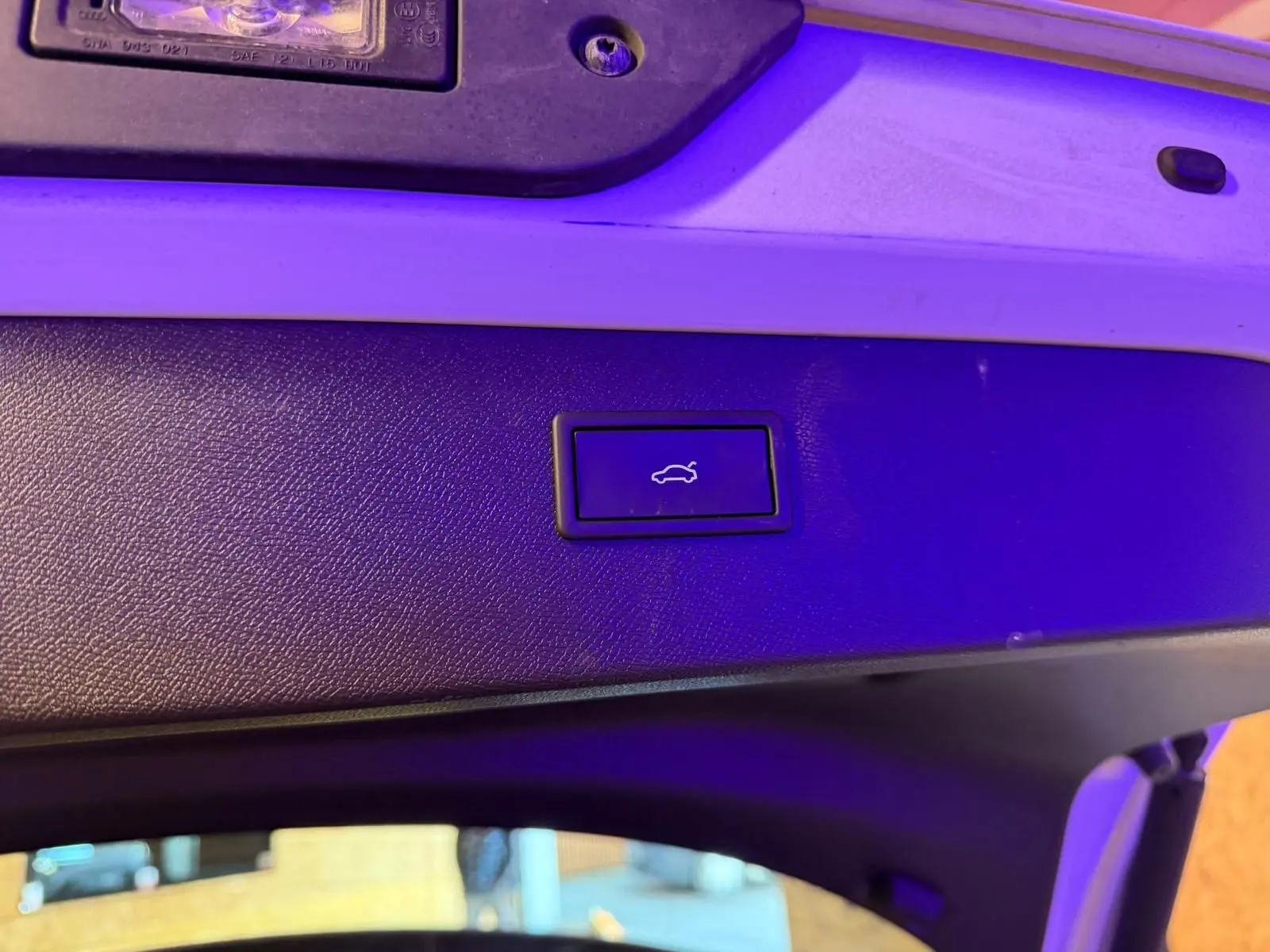 Gros plan sur le bouton d'ouverture électrique du hayon, sur la partie intérieure blanche du coffre du CUPRA Formentor blanc.