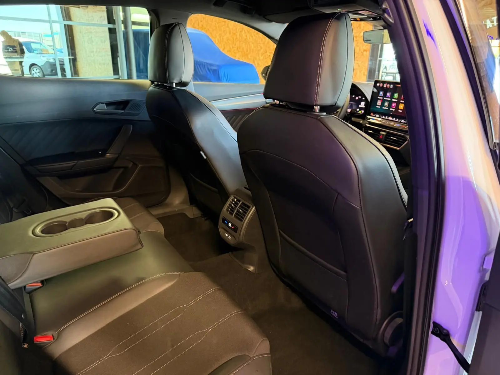 Vue intérieure arrière droite de la CUPRA Formentor 2025 blanche, montrant les sièges en cuir noir et l'accoudoir central rabattable.