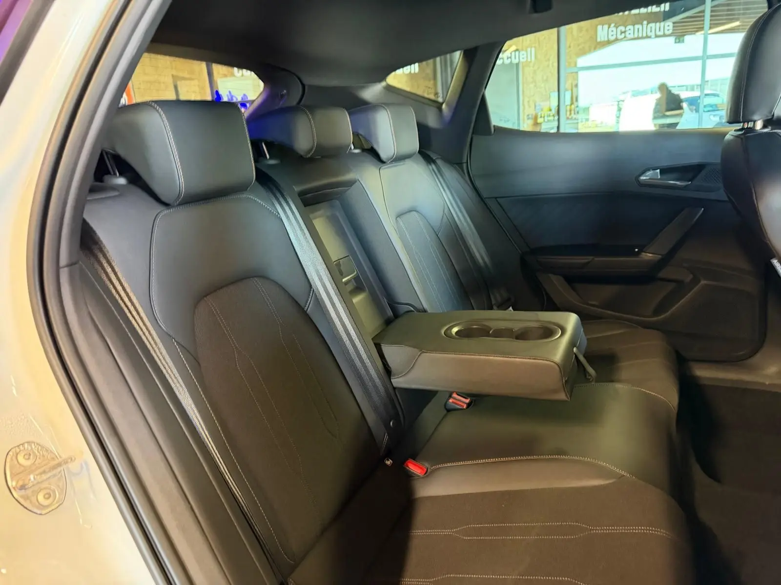 Vue intérieure côté gauche des sièges arrière noirs avec accoudoir central relevé du CUPRA Formentor blanc 2025.