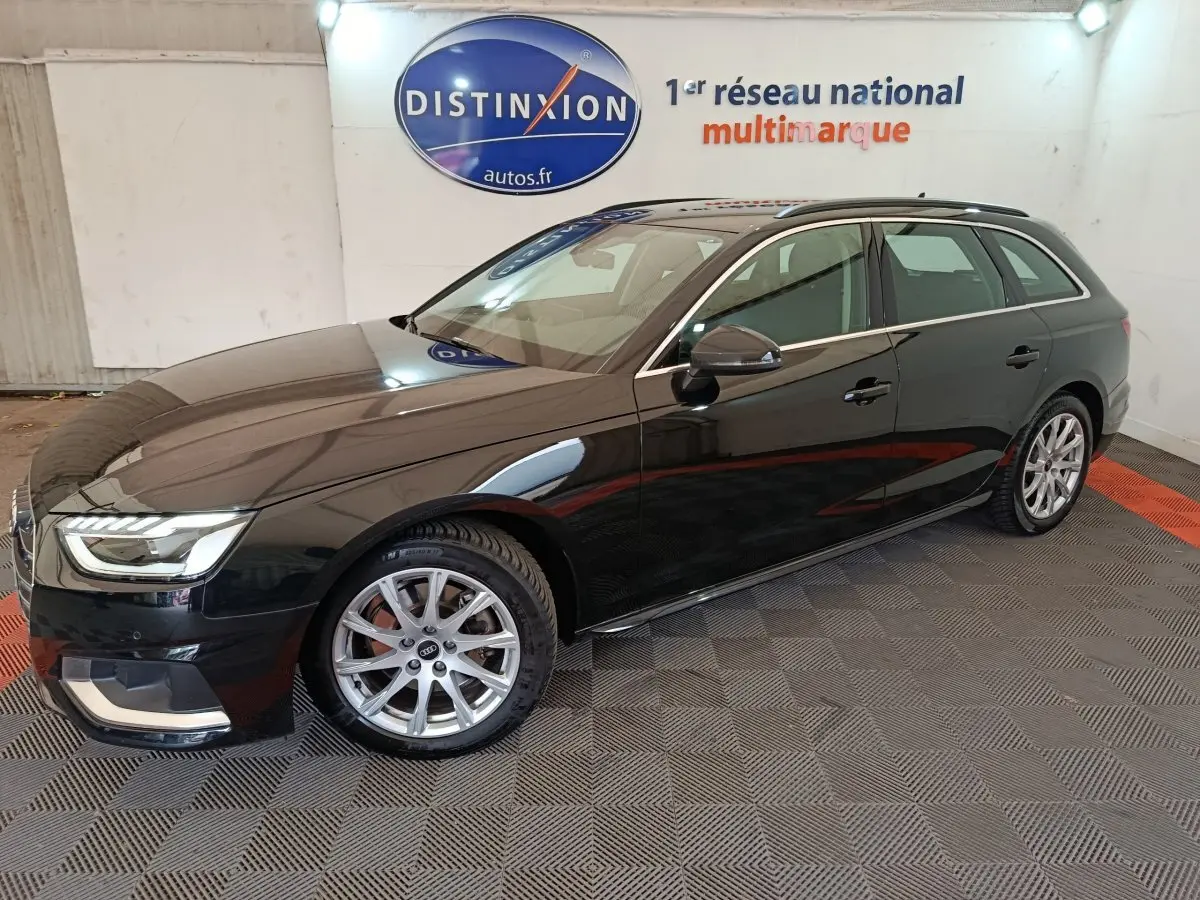 Audi A4 35 TFSI Business Line noire vue de profil droit en stationnement intérieur sur sol damier.