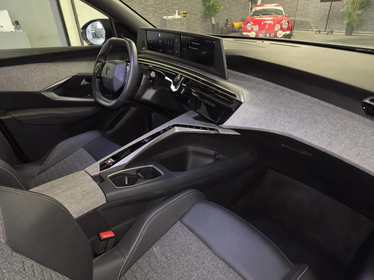 Intérieur de la Peugeot 3008 Hybrid 2025 vu côté passager, avec tableau de bord et console centrale en tissu gris chiné.
