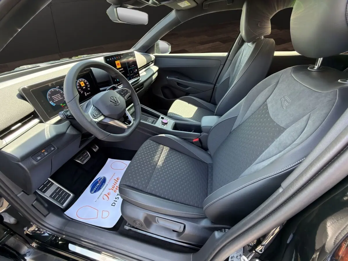 Vue intérieure côté conducteur du Volkswagen T-Roc noir 2026, avec sièges R-Line et tableau de bord digital.