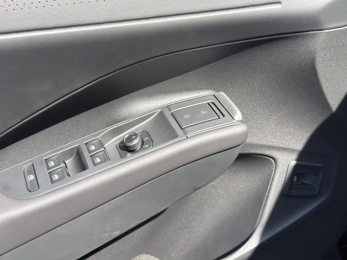Gros plan sur la commande des vitres et rétroviseurs côté conducteur du Volkswagen T-Roc noir, intérieur moderne.