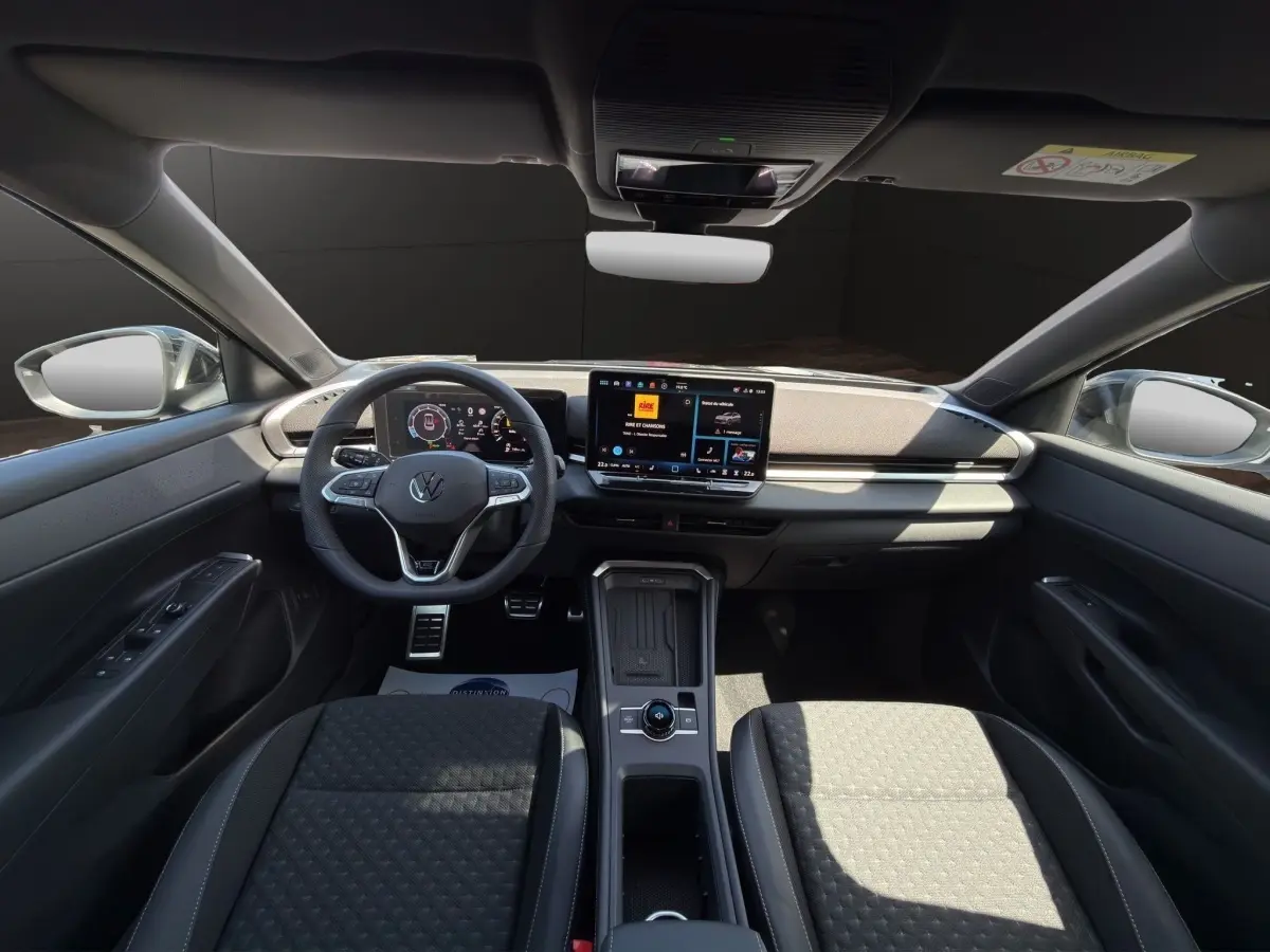 Vue intérieure avant du Volkswagen T-Roc noir 2026, mettant en valeur le tableau de bord digital et l'écran tactile central.