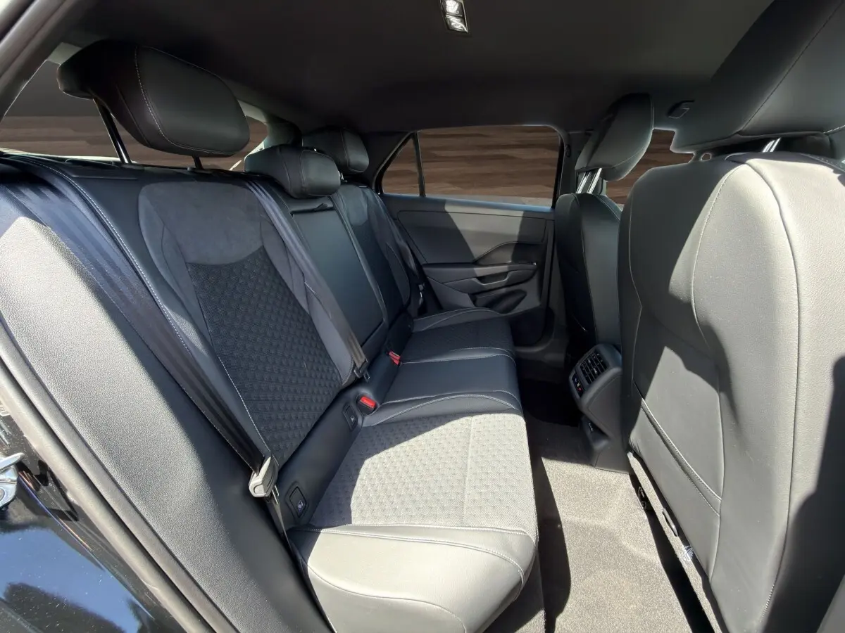 Vue intérieure côté droit des sièges arrière noirs du Volkswagen T-Roc 1.5 eTSI R-Line avec accoudoir central et aérateurs.