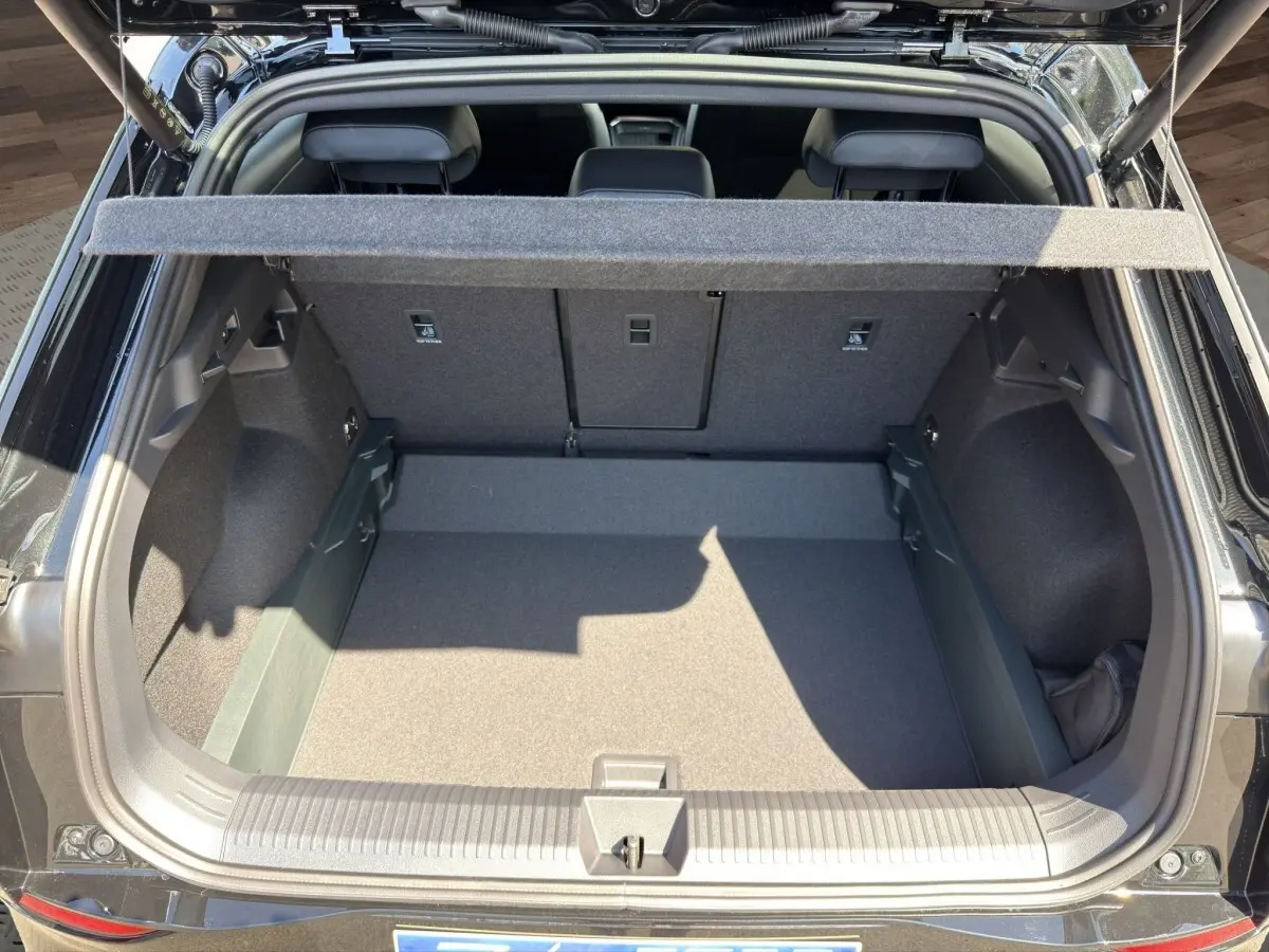 Vue arrière du coffre ouvert d'un Volkswagen T-Roc noir 2026, montrant l'espace de chargement et la tablette cache-bagages.