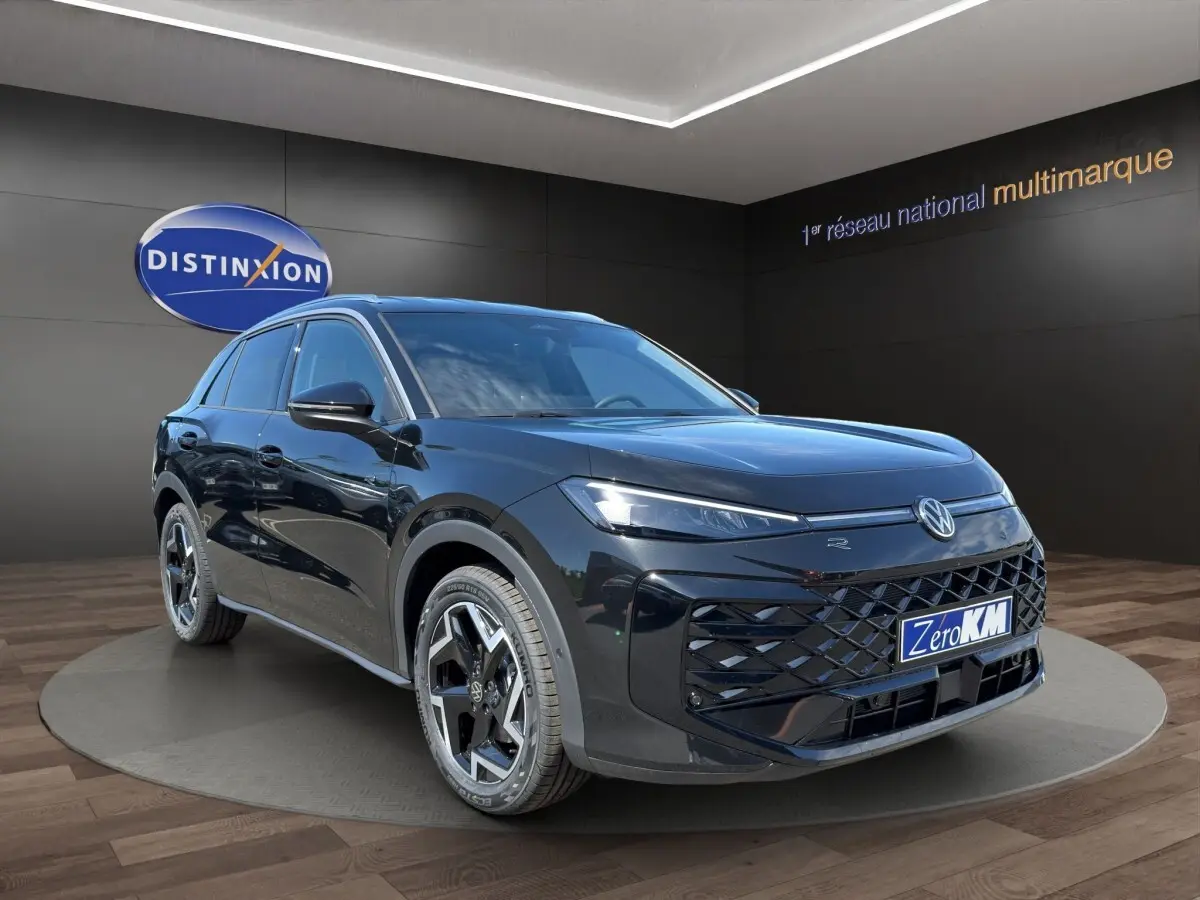 Volkswagen T-Roc noir en 3/4 avant droit avec calandre R-Line et jantes distinctives sur podium showroom.