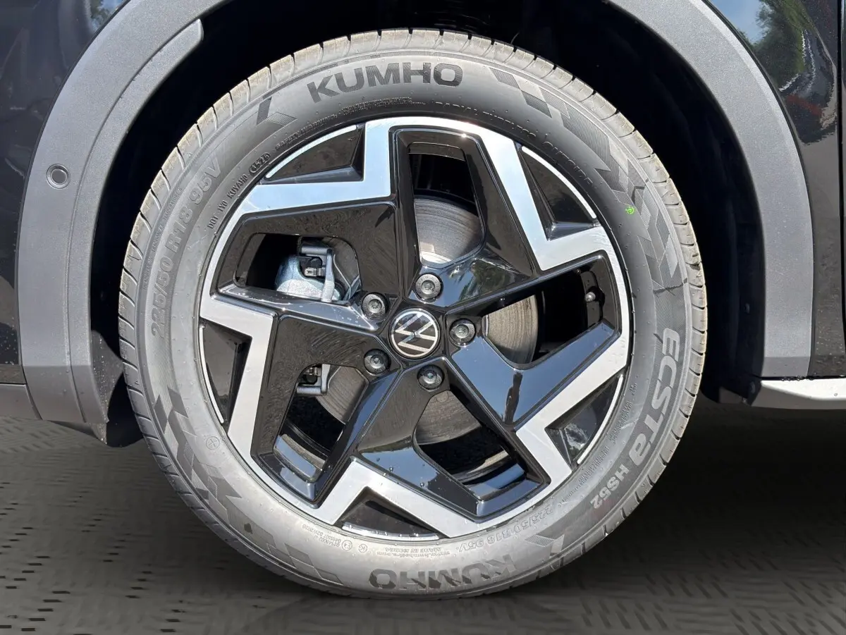 Gros plan sur la roue avant droite noire du Volkswagen T-Roc 1.5 eTSI EVO2 avec jante alliage et logo VW central.