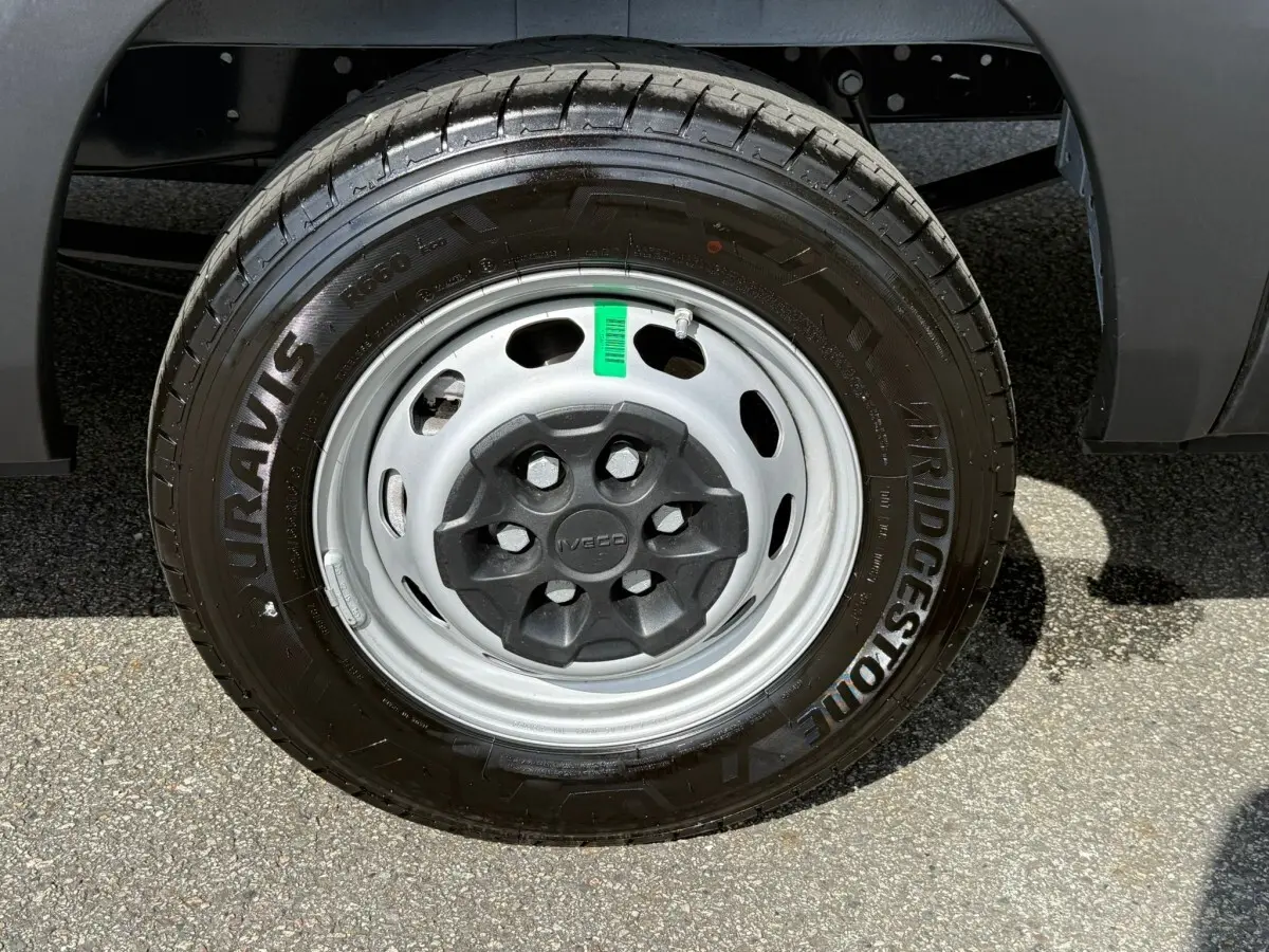 Gros plan sur la roue avant droite d’un Iveco Daily blanc, pneu Bridgestone et jante acier grise.