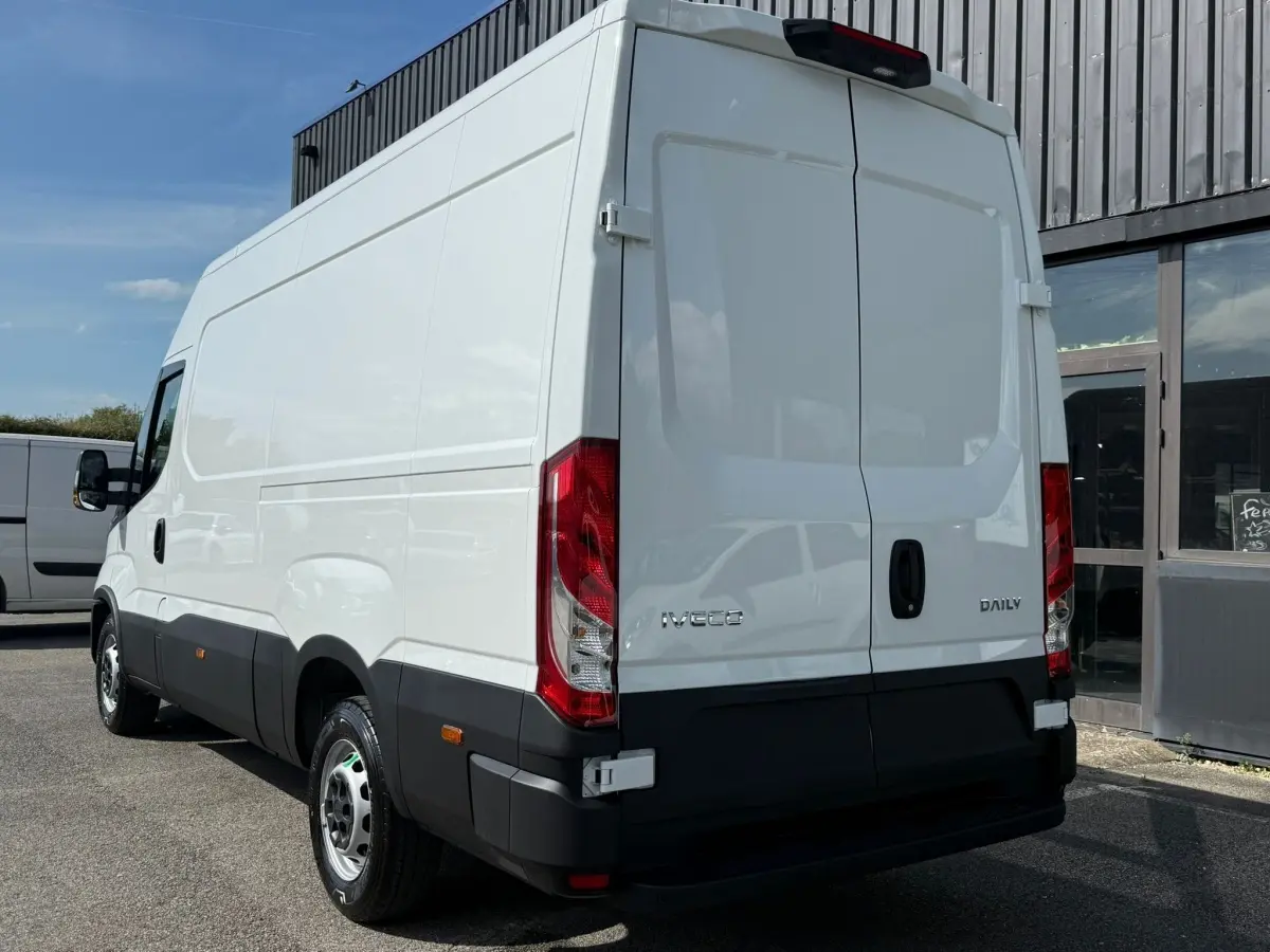 Vue 3/4 arrière droite d’un utilitaire Iveco Daily blanc avec portes arrière fermées et feux rouges visibles.