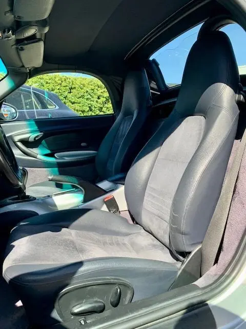Intérieur de la Porsche Boxster 986 3.2 S gris de 2001, vue côté conducteur montrant les sièges en tissu et cuir.