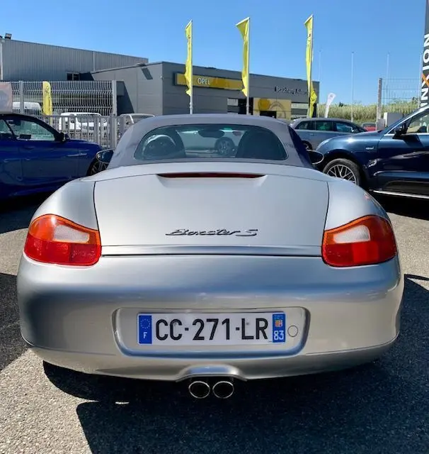 Vue arrière d'une Porsche Boxster S 986 gris 2001 avec capote grise et double sortie d'échappement centrale.